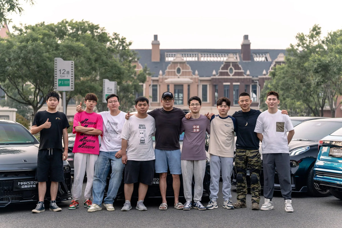 MAKSTTON owners gathered beside their cars outside a brick building — Qingdao, Shandong, China, 2024