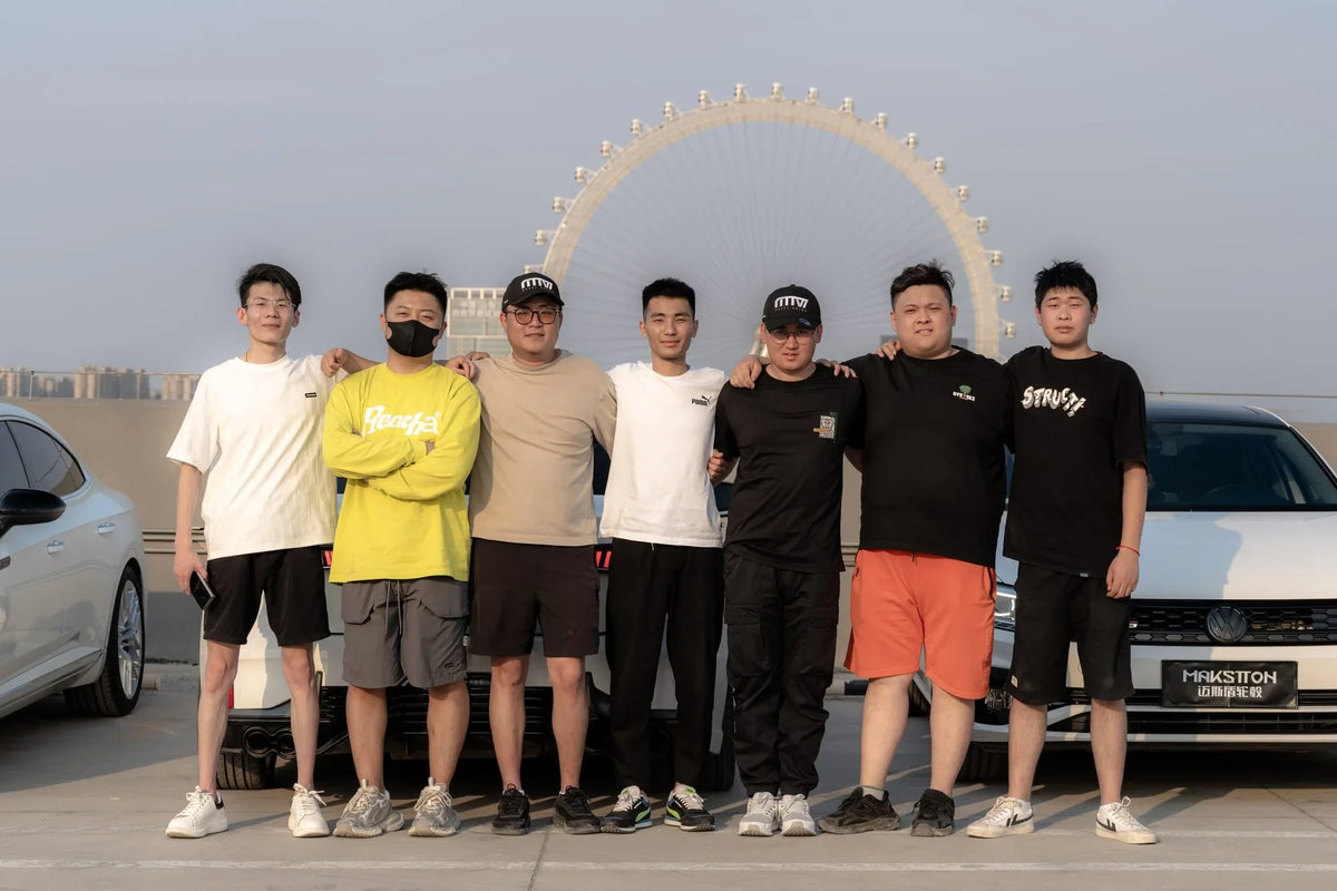 MAKSTTON owners gathered beside their cars with a Ferris wheel behind them — Jinan, Shandong, China, 2024