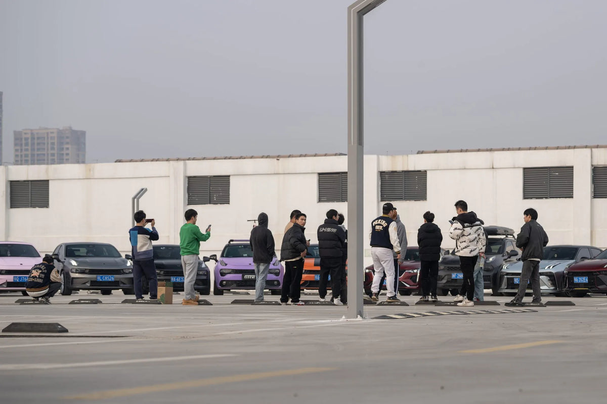 MAKSTTON owners standing beside a lineup of cars in an open parking area — Wuhan, Hubei, China, 2024