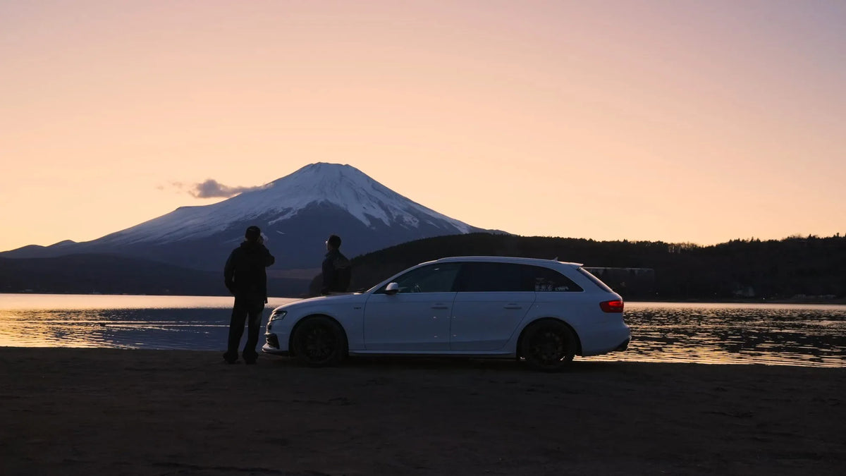 A white estate car and two people beside a lake at sunset with Mount Fuji behind them — Tokyo, Tokyo, Japan, 2025